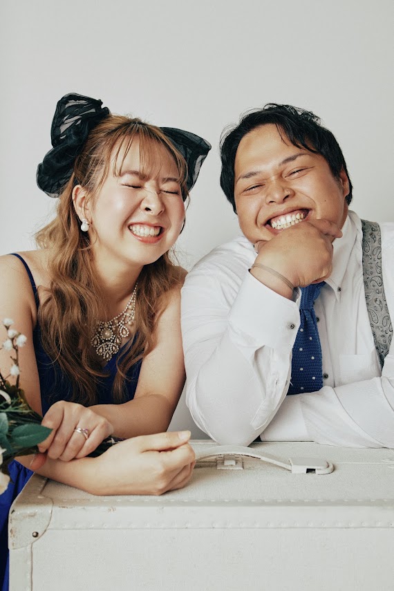 白背景のスタジオで並んで笑う新郎新婦