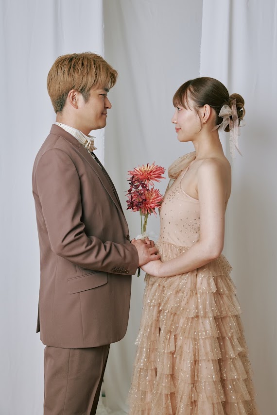 花を持って向かい合うカジュアル衣装の新郎新婦