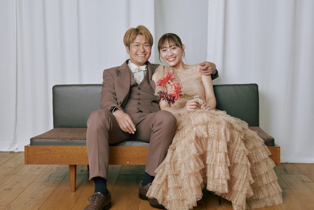 ソファに並んで笑うカジュアル衣装の新郎新婦