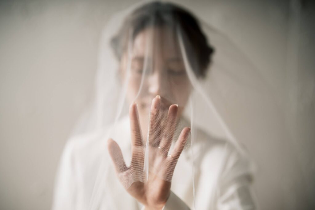 ベール越しに指輪をつけた手を見せる女性のポートレート