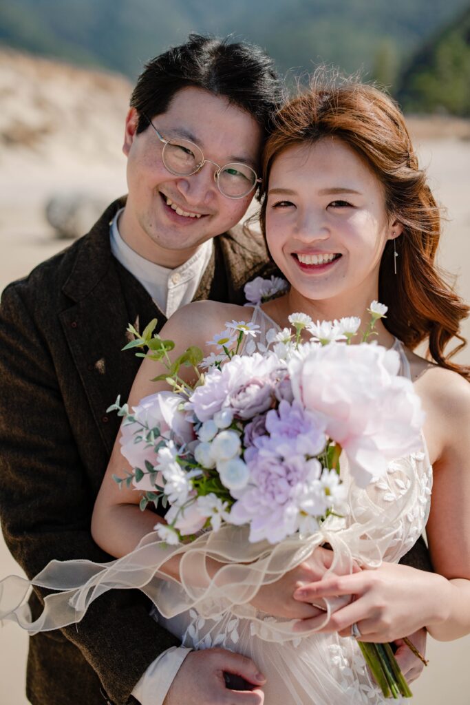花束を手に笑顔を見せる新郎新婦のロケーションウェディングフォト